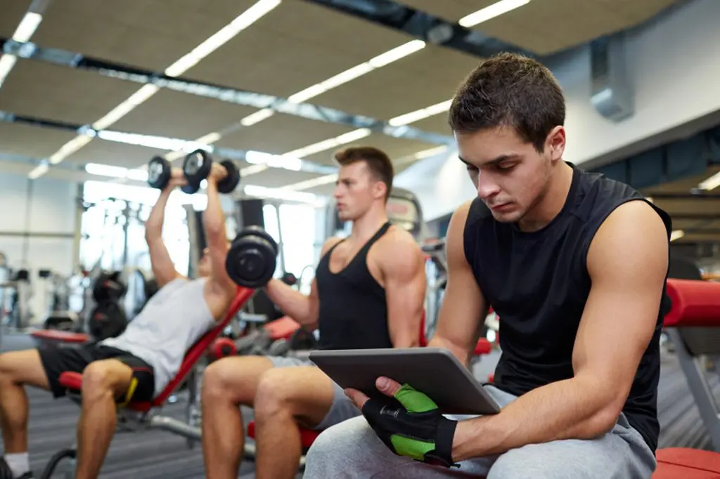 A group of men in gym using laptop computers.