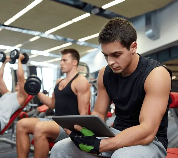 A man sitting on the floor of an indoor gym.