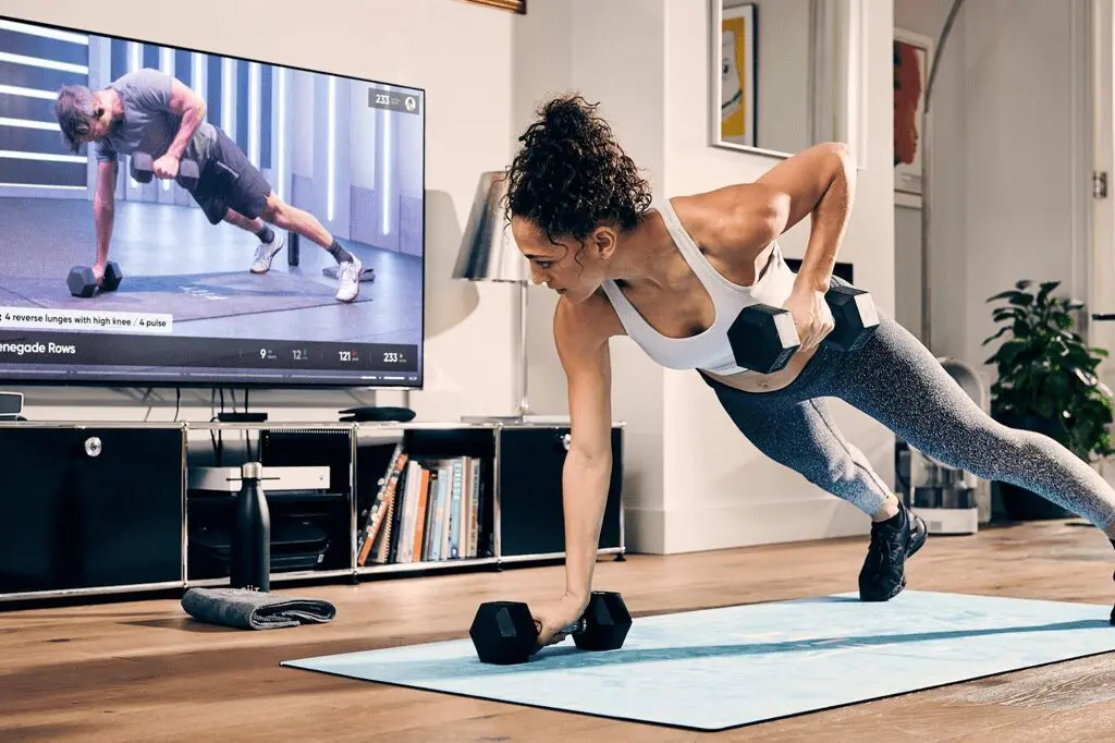 A woman is doing push ups in front of the tv.