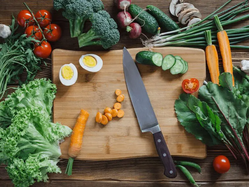 A cutting board with an egg and some vegetables on it