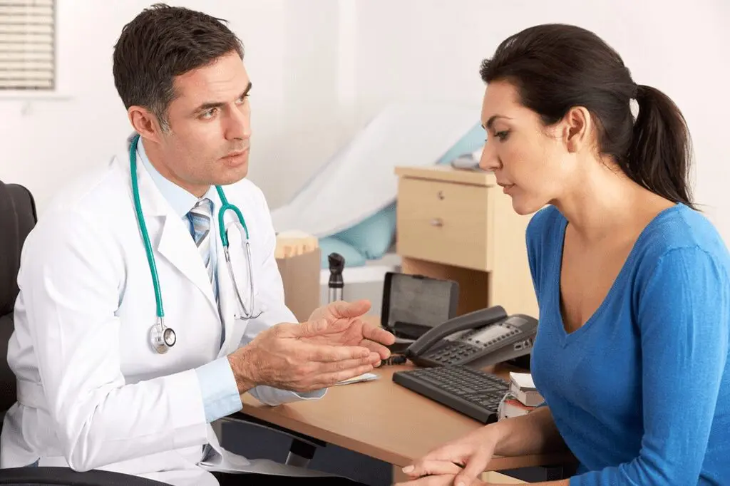 A doctor talking to a woman in an office setting.