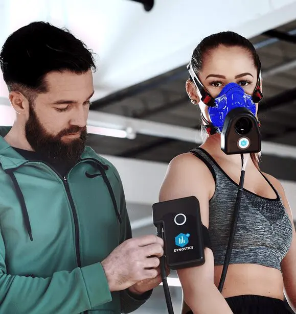 A man and woman wearing masks while holding a device.