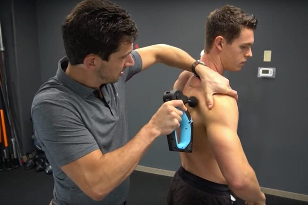 A man is using an electric device to treat his shoulder.