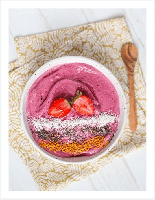 A bowl of smoothie with strawberries and coconut.