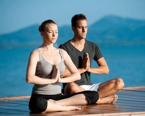 A man and woman sitting in the lotus position.