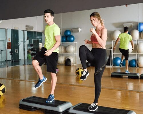 A man and woman are doing exercises on step boards.